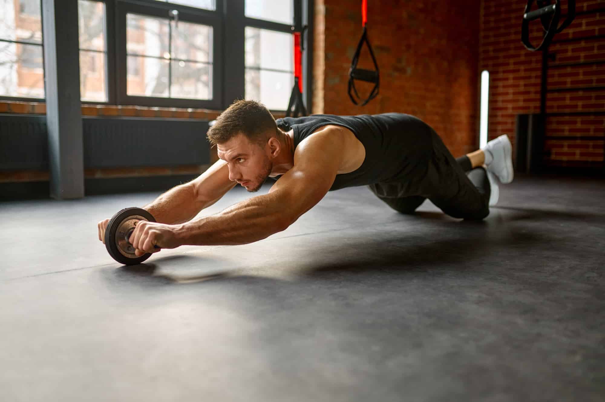 Man training with bare torso abs wheel