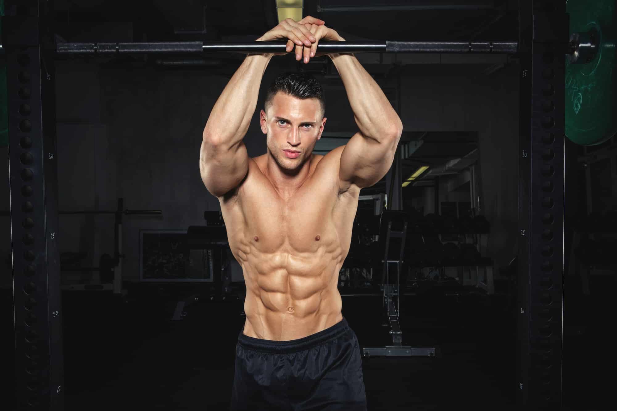 Physical athlete leaning at Power Rack in gym